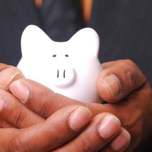 Person holding a white piggy bank