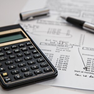 Calculator, invoice and pen scattered on table
